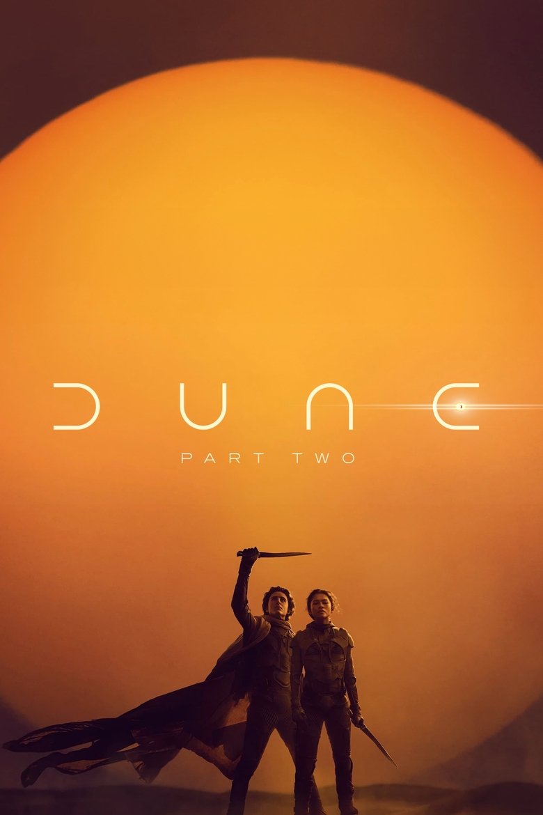 Still from Dune: Part Two showing Paul Atreides standing atop a massive sand dune, looking out at a vast, desolate landscape.
