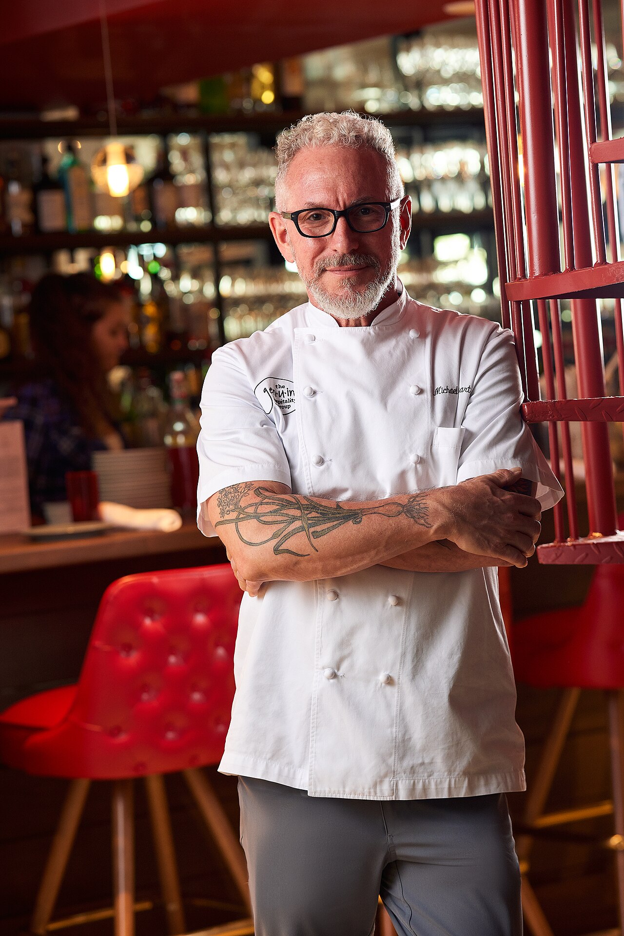 Chef Michael Schwartz in the kitchen of Michael's Genuine Food & Drink, plating a dish with concentration.